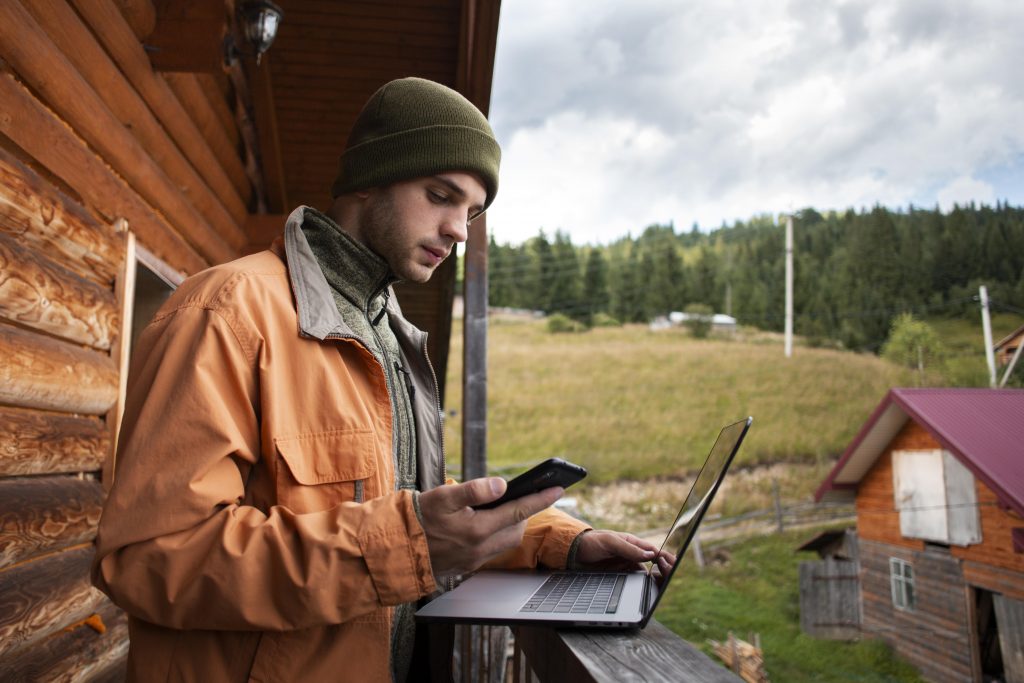 Man with laptop and cell phone in rural area